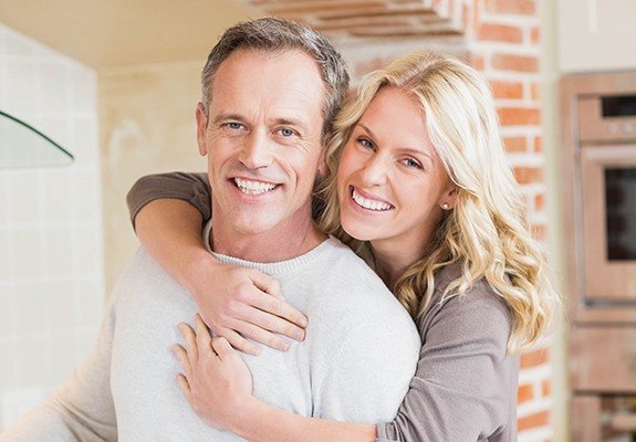 Smiling older man and woman in kitchen hugging