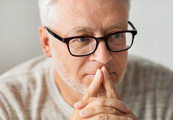 Man with glasses looking contemplative