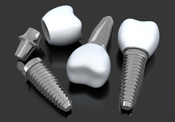 Three dental implants and dental crowns lying on table