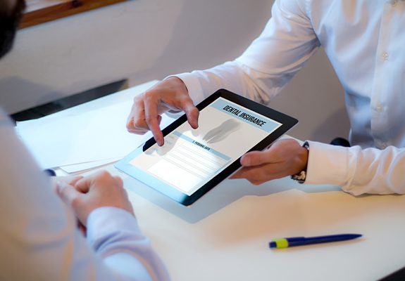 Two people looking at dental insurance forms on tablet computer