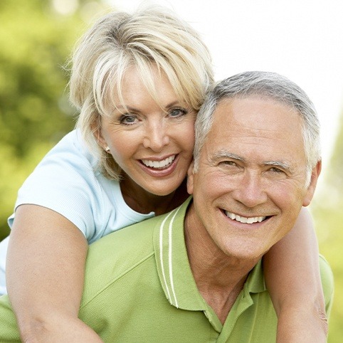 Older man and woman smiling outdoors after receiving periodontal services in North Bethesda