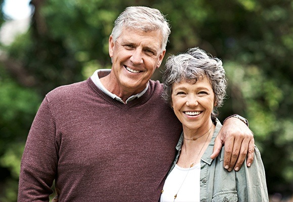 Older man and woman smiling outdoors after receiving oral surgery services in North Bethesda