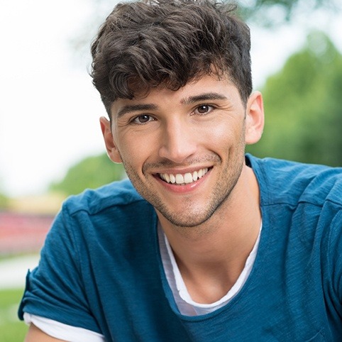 Young man smiling outdoors after wisdom tooth extractions