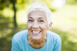 senior woman proudly smiling with dental implants in North Bethesda